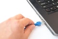 Hand putting a blue RJ45 network connecting cable to a laptop