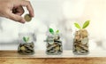 Hand putting coin in glass bottles with plants glowing, Saving money, and investment concepts