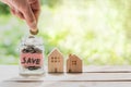 Hand putting coin in glass jar of coin for saving money for buying house. Royalty Free Stock Photo