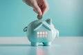 Hand putting a coin in piggy bank in a shape of a house. Saving money for buying a home, financial literacy. Budgeting, savings Royalty Free Stock Photo