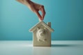 Hand putting a coin in piggy bank in a shape of a house. Saving money for buying a home, financial literacy. Budgeting, savings Royalty Free Stock Photo