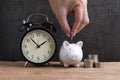 Hand putting coin into piggy bank with stack of coins beside and Royalty Free Stock Photo