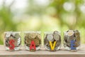 Hand putting coins into clear money jar on wooden table with green blur light background. Savings concept Royalty Free Stock Photo