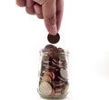 Hand putting coins in a glass jar