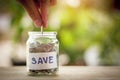 Hand putting coins in a jar. Saving money concept and save money to support everything in life with sun light bokeh background