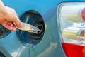 Hand putting Euro money bills in car fuel tank. Transportation expenses concept. Fuel tank filled with money symbolizing the high Royalty Free Stock Photo