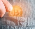 Hand putting bitcoin into pocket, close-up.