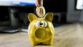 Hand putting golden bitcoin in to piggy bank money box with a computer on background. Cryptocurrency investment concept