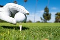 Hand putting golf ball on tee in golf course. Golf ball in grass. Golf ball on tee ready to be shot. Royalty Free Stock Photo