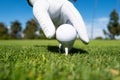 Hand putting golf ball on tee in golf course. Golf ball in grass. Golf ball on tee ready to be shot. Royalty Free Stock Photo