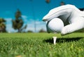 Hand putting golf ball on tee in golf course. Golf ball in grass. Golf ball on tee ready to be shot. Royalty Free Stock Photo