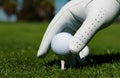 Hand putting golf ball on tee in golf course. Golf ball in grass. Golf ball on tee ready to be shot. Royalty Free Stock Photo