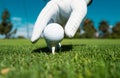 Hand putting golf ball on tee in golf course. Golf ball in grass. Golf ball on tee ready to be shot. Royalty Free Stock Photo