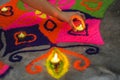 A hand putting a lamp on a beautiful and colorful rangoli on Diwali/Deepavali Celebration