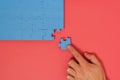 Hand putting the last piece of blue jigsaw puzzle on red background Royalty Free Stock Photo