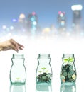 Hand putting mix coins and seed in clear bottle on cityscape photo Royalty Free Stock Photo