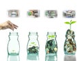 Hand putting mix coins and seed in clear bottle with step of construction house Royalty Free Stock Photo