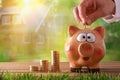 Hand putting money into piggy bank to buy a house Royalty Free Stock Photo