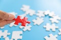 Hand putting piece of red jigsaw puzzle on blue background. Team business success partnership or teamwork Royalty Free Stock Photo