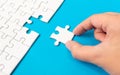Hand putting piece of white jigsaw puzzle on blue background. Team business success partnership or teamwork Royalty Free Stock Photo