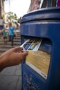 Hand putting a postcard in a Blue Guernsey Post Box unique to Guernsey in the town of St Pierre Port St Peter Port, the main Royalty Free Stock Photo