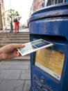 Hand putting a postcard in a Blue Guernsey Post Box unique to Guernsey in the town of St Pierre Port St Peter Port, the main Royalty Free Stock Photo