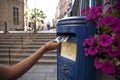 Hand putting a postcard in a Blue Guernsey Post Box unique to Guernsey in the town of St Pierre Port St Peter Port, the main Royalty Free Stock Photo