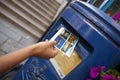 Hand putting a postcard in a Blue Guernsey Post Box unique to Guernsey in the town of St Pierre Port St Peter Port, the main Royalty Free Stock Photo