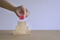 Hand putting a red wood block on stack of pyramid wood blocks Royalty Free Stock Photo