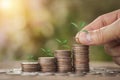 Hand putting stack coins for growing with sun light bokeh background and tree growing on coin. Royalty Free Stock Photo