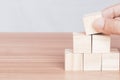 Hand putting and stacking blank wooden cubes on the table with copy space. Hand arranging wood block stacking as step stair.