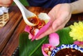 Hand Putting Sweet and Spicy Dip into Thai Style Fresh Lotus Petal Wrapped Appetizer Holding in Hand