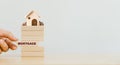 Hand putting wooden block with word mortgage and wood house with coins stack on top Royalty Free Stock Photo