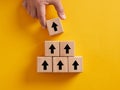 Hand putting wooden cubes with arrow icons pointing upwards