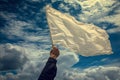 hand raises a white flag against the sky Royalty Free Stock Photo