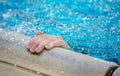 Hand reaches out of a swimming pool