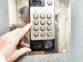 Person pressing a button on a digital intercom system outside a building during midday Royalty Free Stock Photo