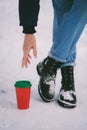 Hand reaches for paper cup standing on the snow