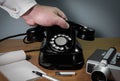 The hand reaches for the phone. Old telephone set on a wooden table, and filmcamera - retro installation Royalty Free Stock Photo