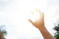 A hand reaches for the sky and covers the sun, the sun`s rays make their way through the hand, close - up, bright sunlight