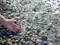 The hand reaches for the water. Sea wave and female hand. Feel the wave. Pebble beach