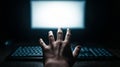 Hand reaching for a glowing computer screen in a dark office, suggesting hacking, cybercrime, or data breach Royalty Free Stock Photo