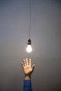 Hand reaching for light bulb Royalty Free Stock Photo