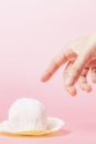 Hand reaching out to pick a delicious strawberry daifuku, Japanese rice cake up against pink background Royalty Free Stock Photo