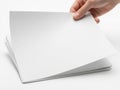 Hand reaching out to a stack of blank white papers on a white background Royalty Free Stock Photo