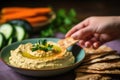 hand reaching for a piece of pita bread beside a bowl of hummus Royalty Free Stock Photo