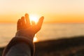 Hand reaching for sun. Sunset sun over the sea. Royalty Free Stock Photo