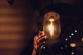 Hand reaching for a vintage light bulb. Royalty Free Stock Photo