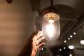 Hand reaching for a vintage light bulb. Royalty Free Stock Photo