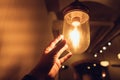 Hand reaching for a vintage light bulb. Royalty Free Stock Photo